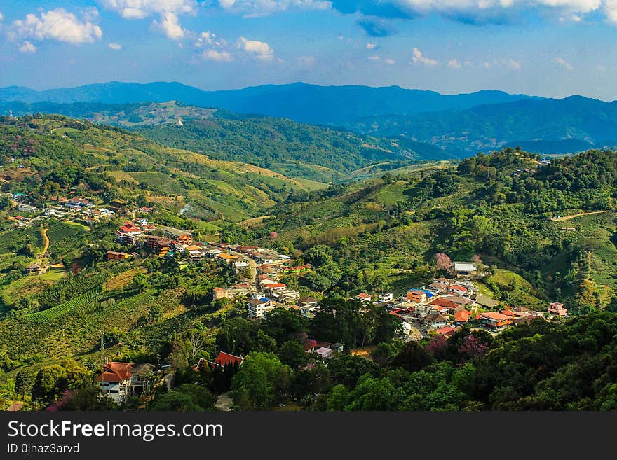 Aerial Photo of City Buildings Beside Green Mountains Under Cloudy Sky