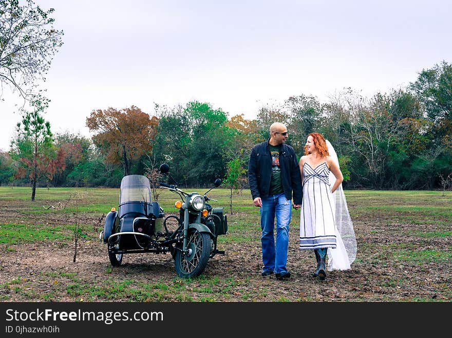 Man and Woman Holding Each Other Hand Beside Grey Motorcycle With Side Trailer