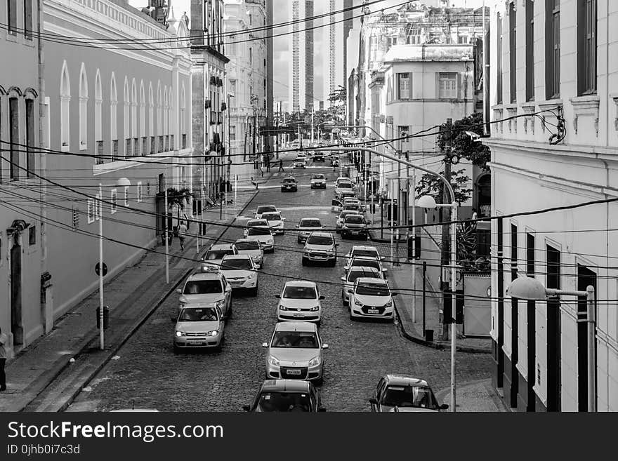 Grayscale Photo of Assorted Cars at the Middle of High Rise Buildings