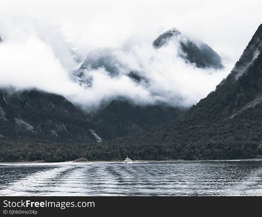 Photography of Body of Water Surrounded by Mountains and Fogs