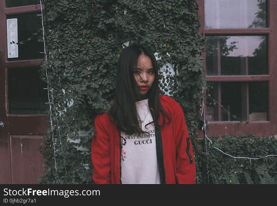 Photo of Woman Standing Near Window Wearing Red Jacket