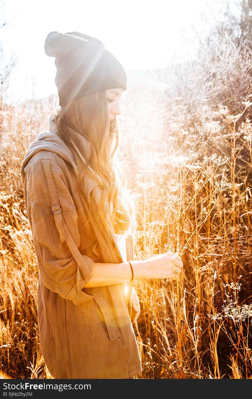 Woman in Black Beanie Standing Next to Tall Grass