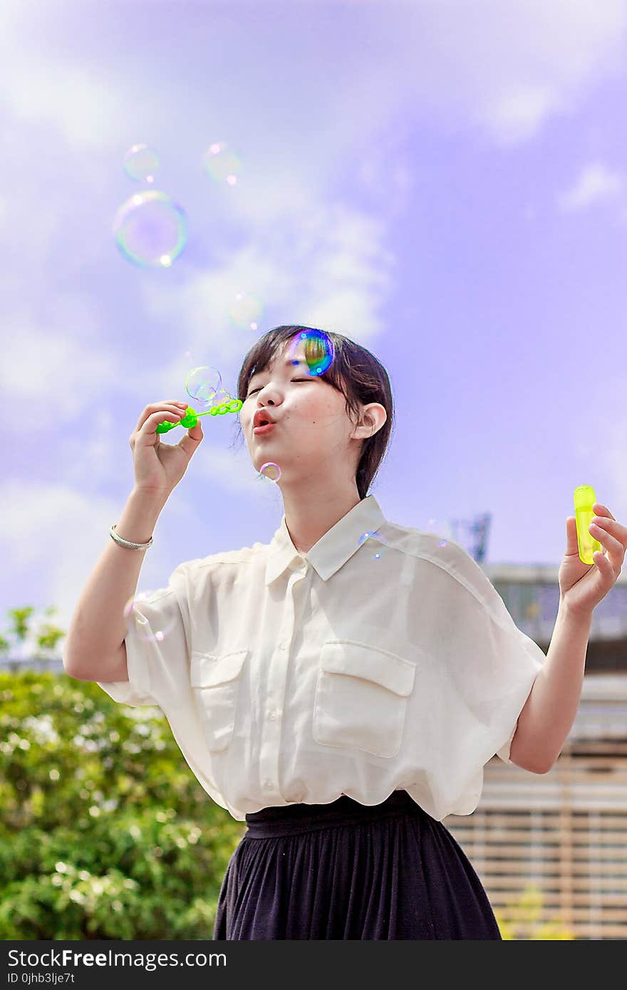 Photo of Woman in White Blouse Playing With Bubbles