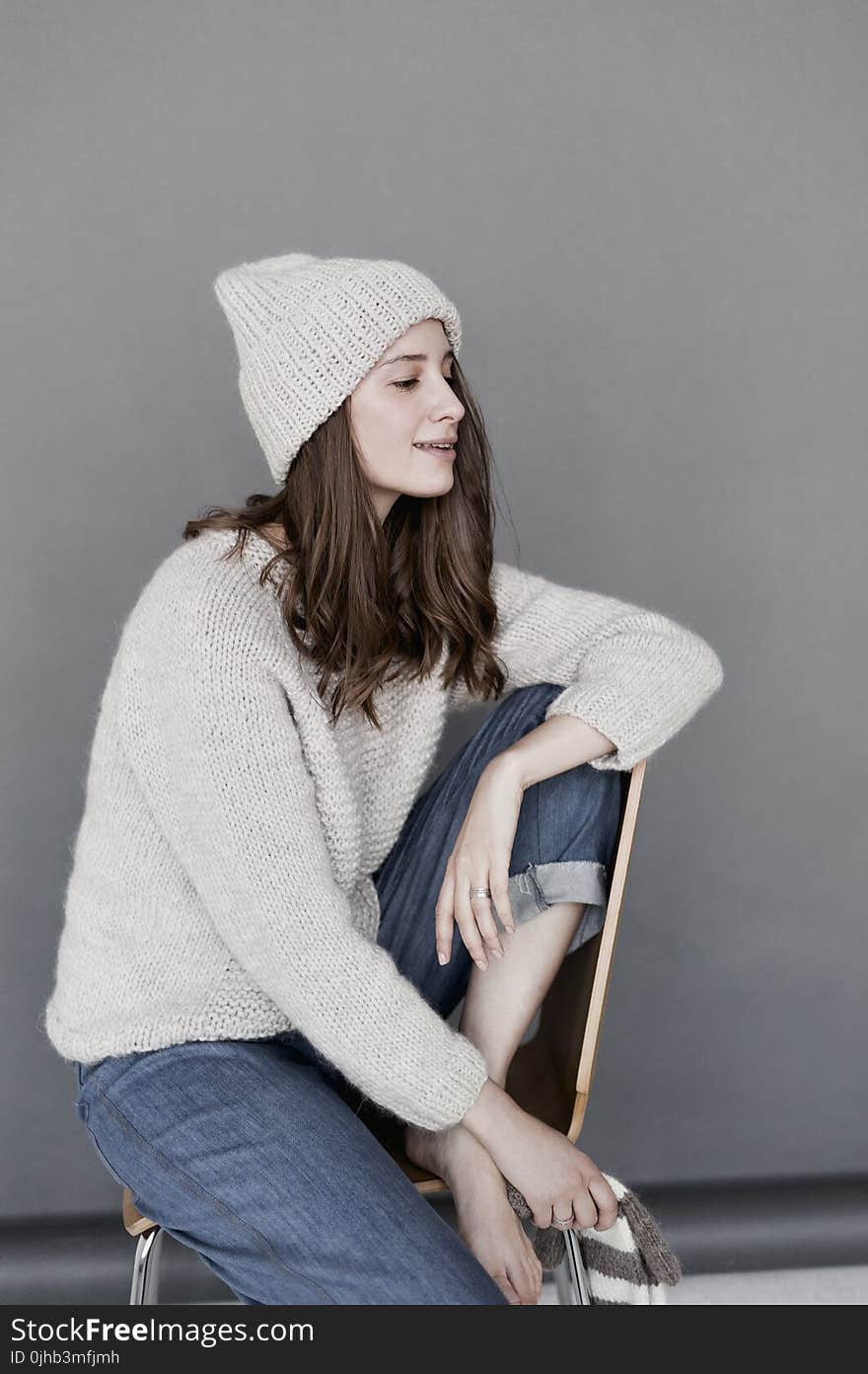 Woman in White Sweater and Beanie With Blue Denim Pants