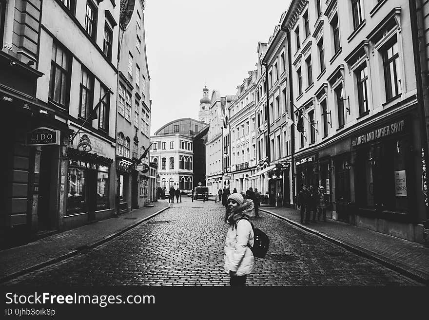 Grayscale Photo of a Woman Between Buildings Photo