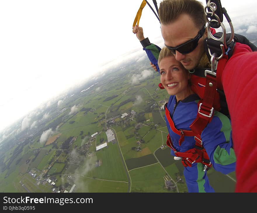 Couple Wears Red and Blue Long-sleeved Overalls and Body Harness With Parachute on Mid-air