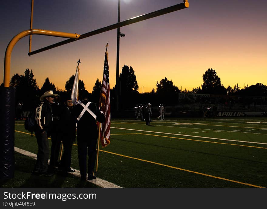 Four People Standing Under on Football Goal during Sunrise