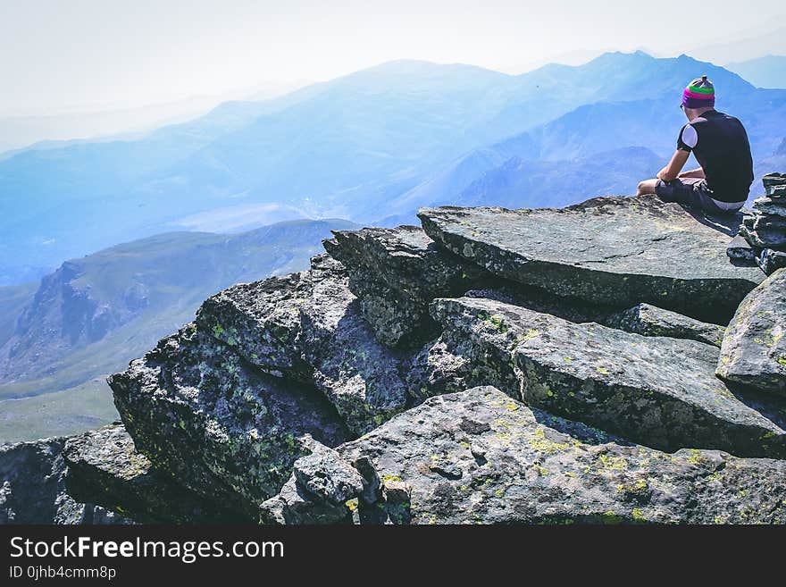 Photography of a Man Sitting on Rock