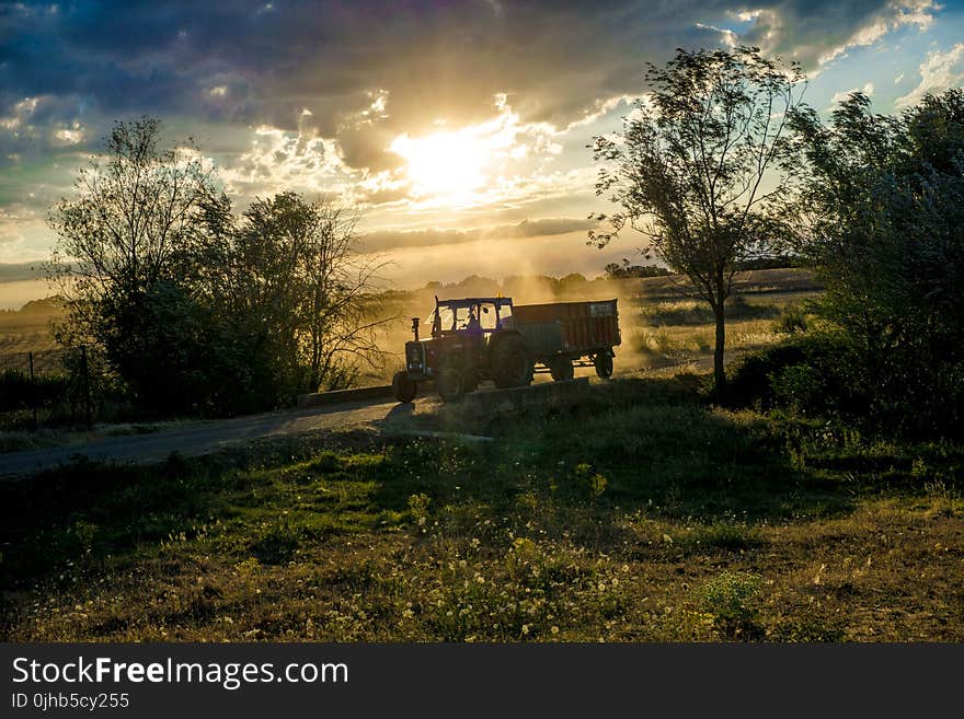 Tractor With Trailer Under Cloudy Skies during Day