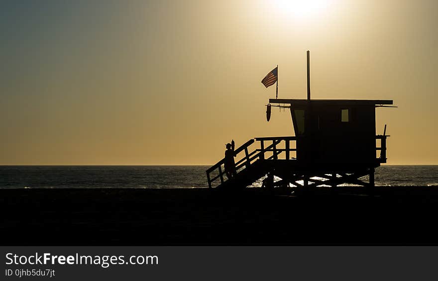 Silhouette of Life Guard House Near Ocean during Sunset