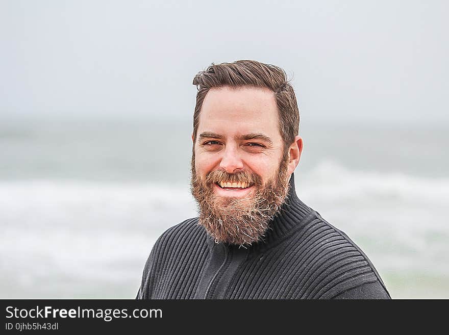 Man Wearing Black Zip-up Jacket Near Beach Smiling at the Photo