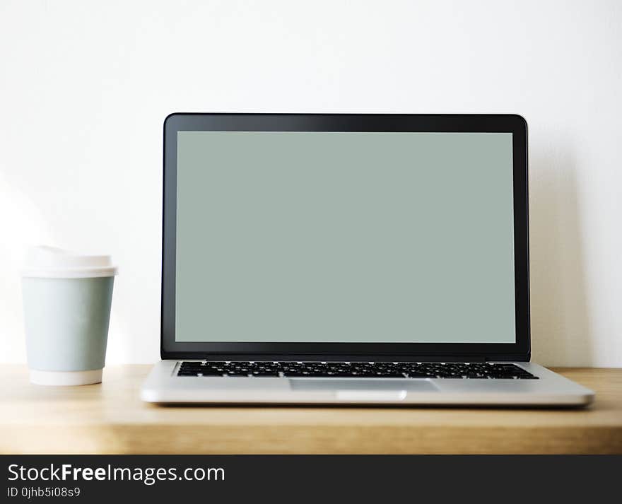 Grey and Black Laptop Beside White and Teal Coffee Cup