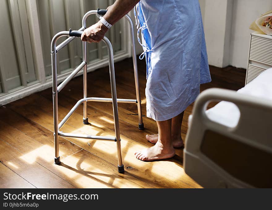 Person in Hospital Gown Using Walking Frame Beside Hospital Bed