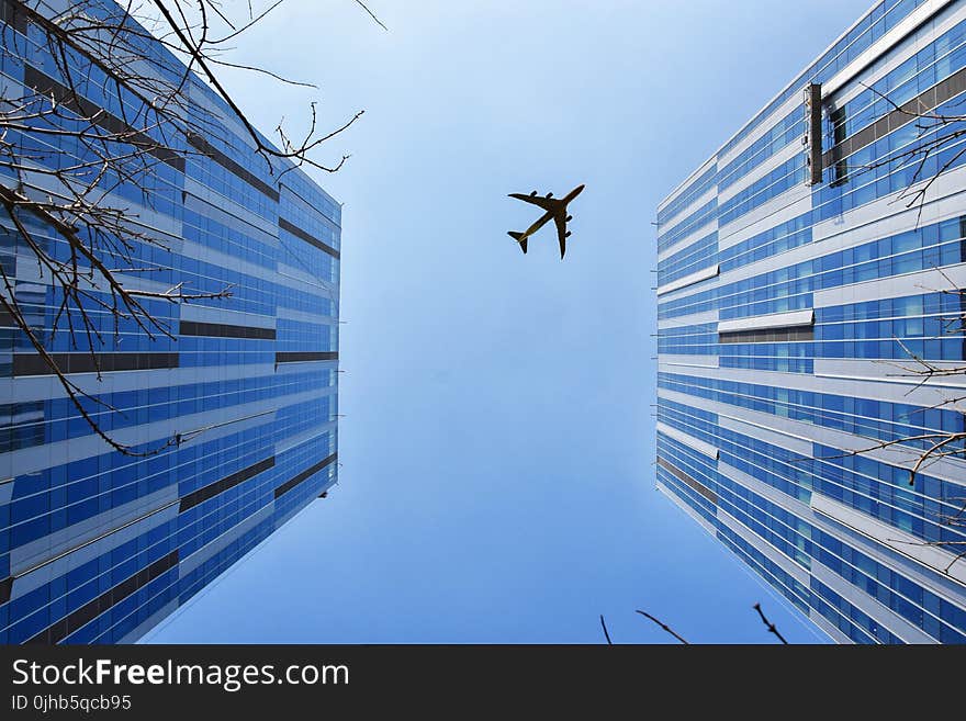 Airplane Near Blue and Grey Building