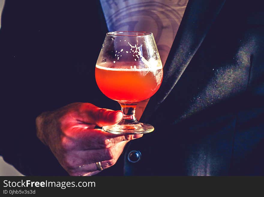 Person Holds Clear Glass Snifter With Red Beverage