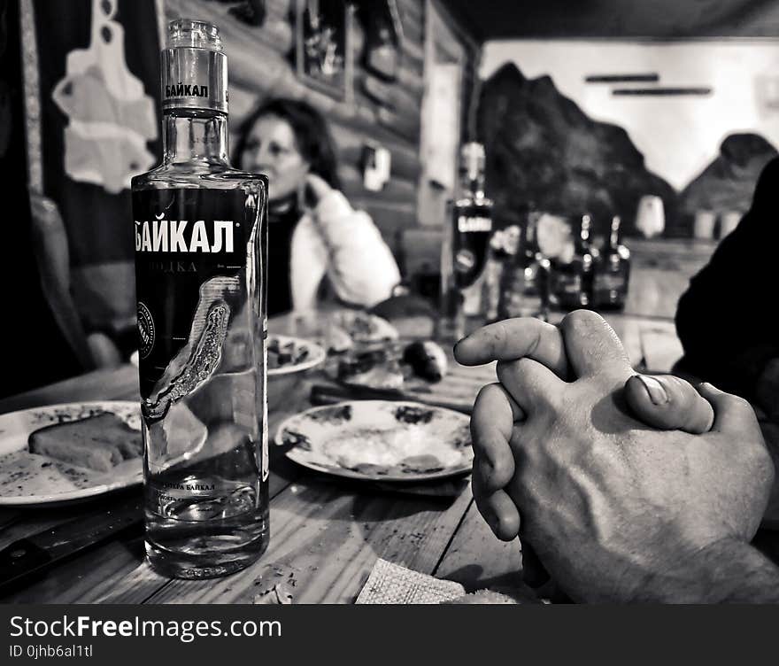 Grayscale Photography of Bottle Beside Saucer