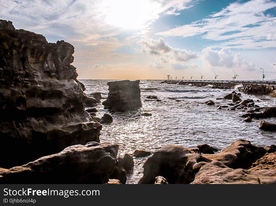 Landscape Photography of Rocks Surrounded by Body of Water