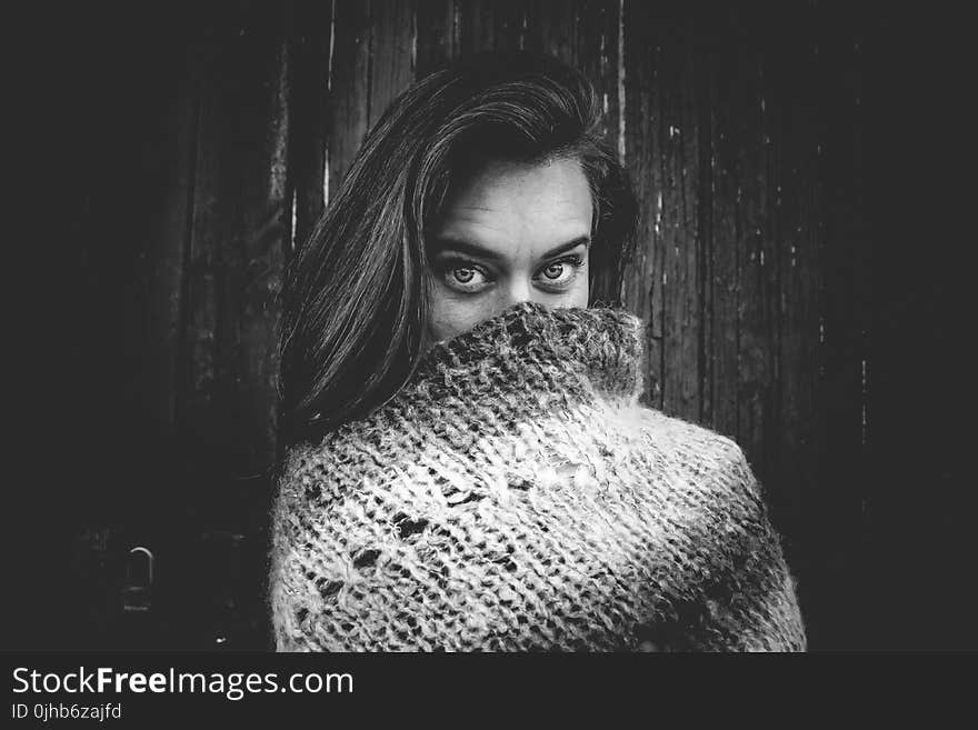 Grayscale Photo of Woman Covering Mouth With Knitted Textile