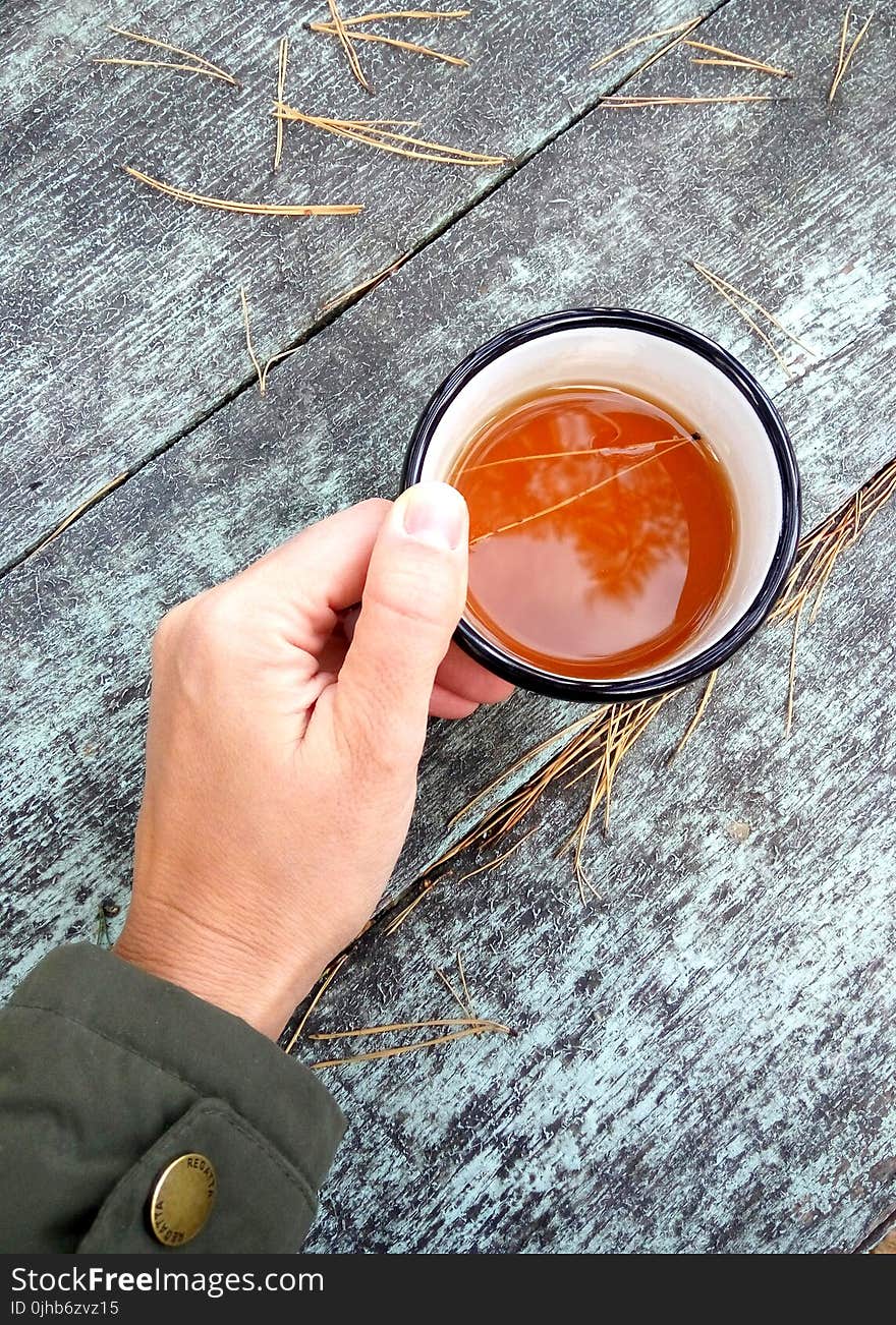 Person Holding Black and White Ceramic Coffee Cup Filled With Coffee