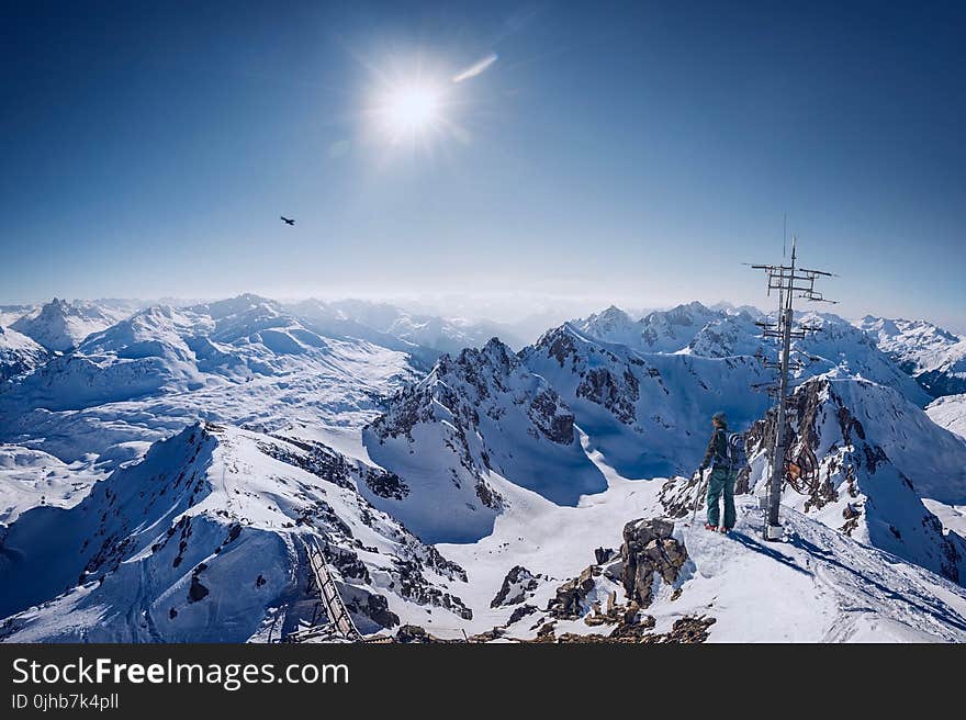 Person on Top of Snow Covered Mountain Under Clear Blue Sky