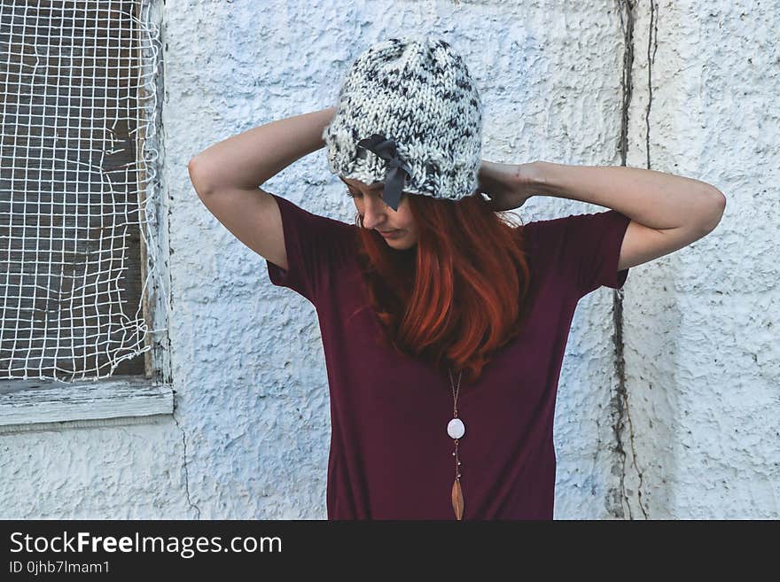 Woman in White and Black Knit Cap Posing Near White Wall