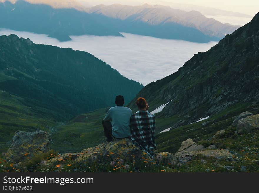 Two Person Sitting on Edge of Mountain Photograph