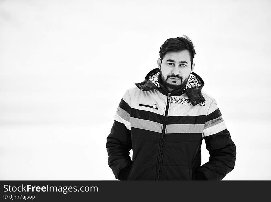 Grayscale Photo of Man Wearing Full-zipped Jacket While Putting His Both Hands Inside Pocket