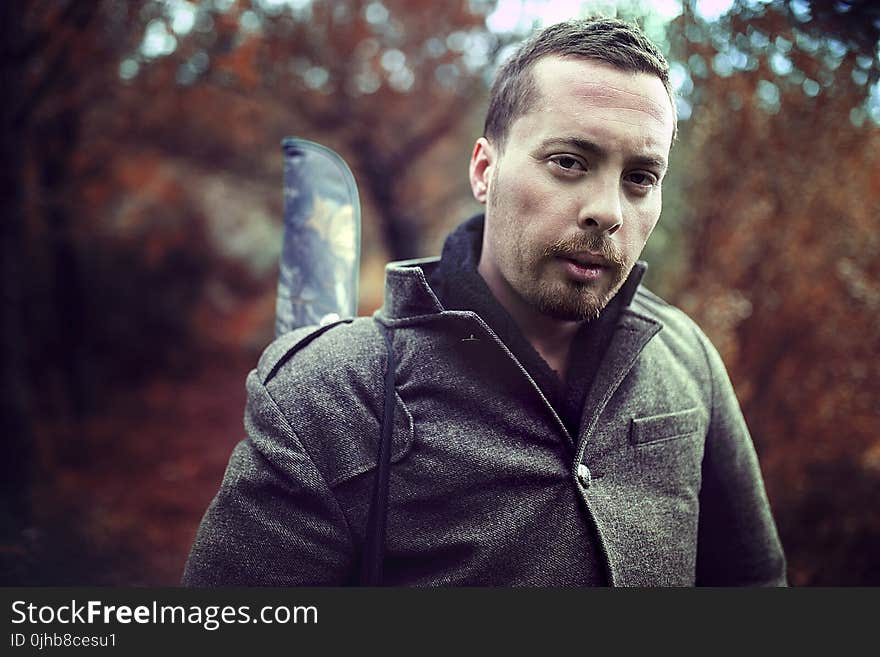 Man Wearing Gray Jacket in Front of Trees