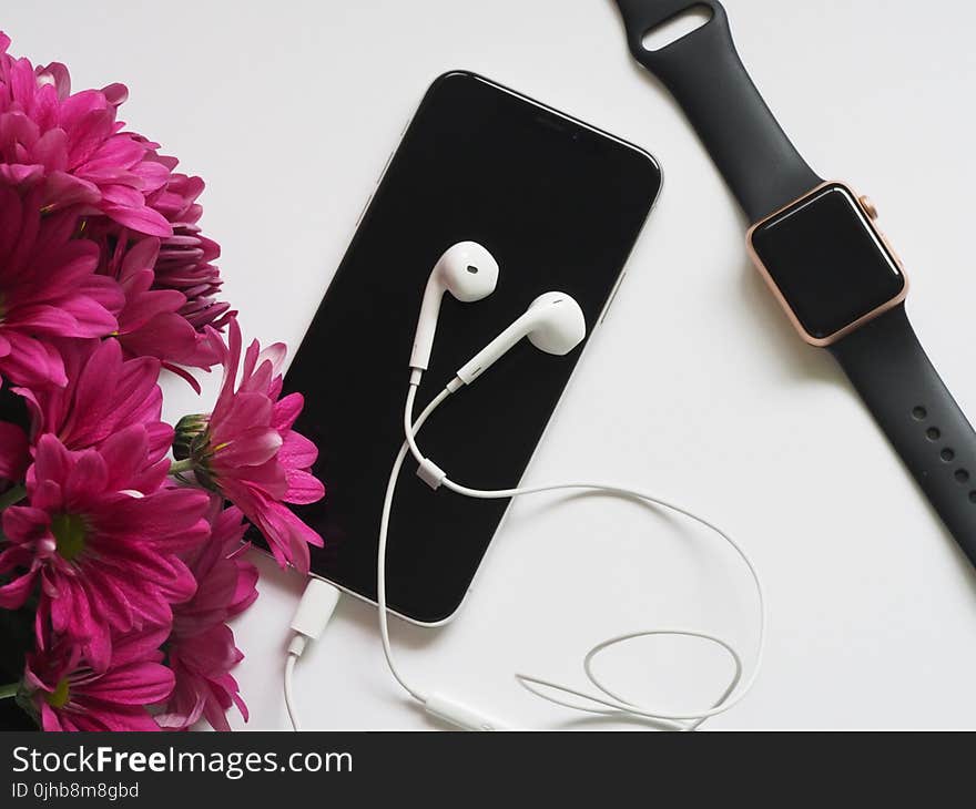 Close-Up Photography of Earphones on Top of Iphone 6 Near Flowers