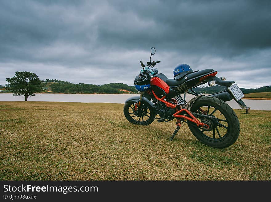 Red and Black Standard Motorcycle on Green Grass Field