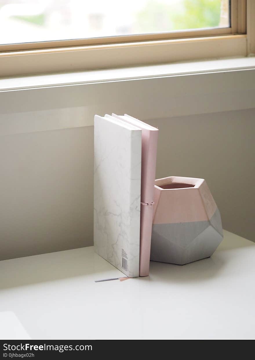 White and Pink Books Piled Beside Pink and Gray Ceramic Vase