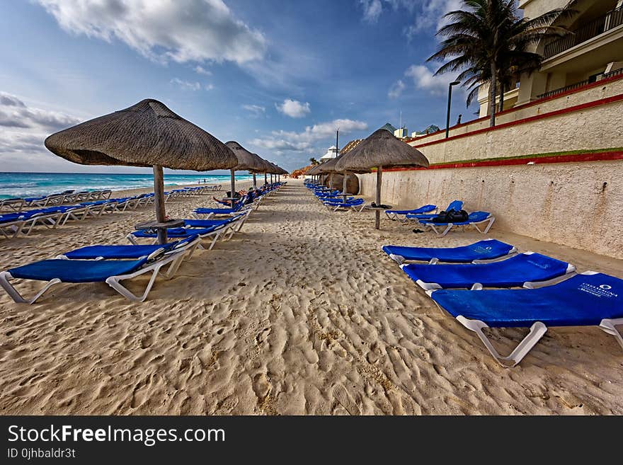 Blue and White Outdoor Chaise Lounges and Nipa Hut Beside Seashore