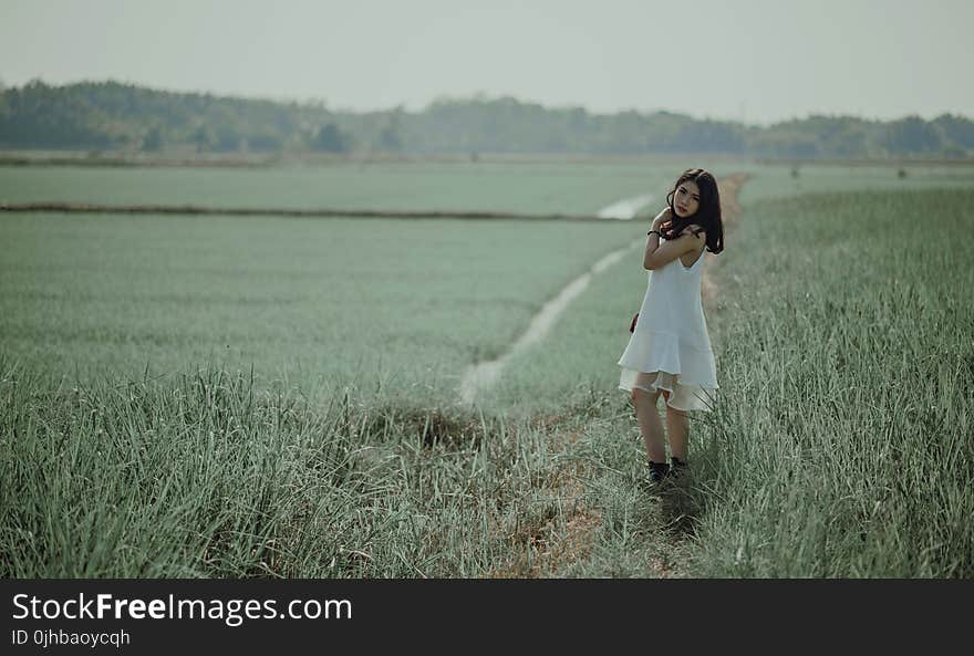 Woman in White Sleeveless Dress on Grass Field