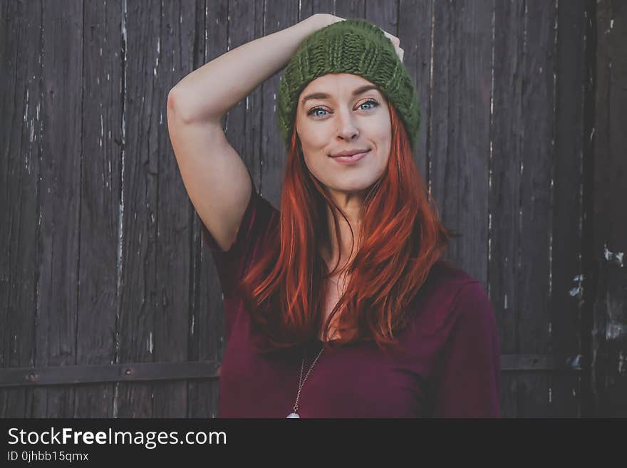 Red Haired Woman in Maroon Top Wearing Green Beanie