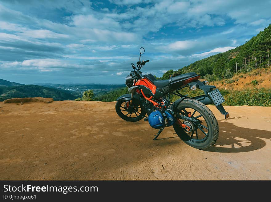 Photography of Orange and Black Sports Motorcycle Near a Cliff