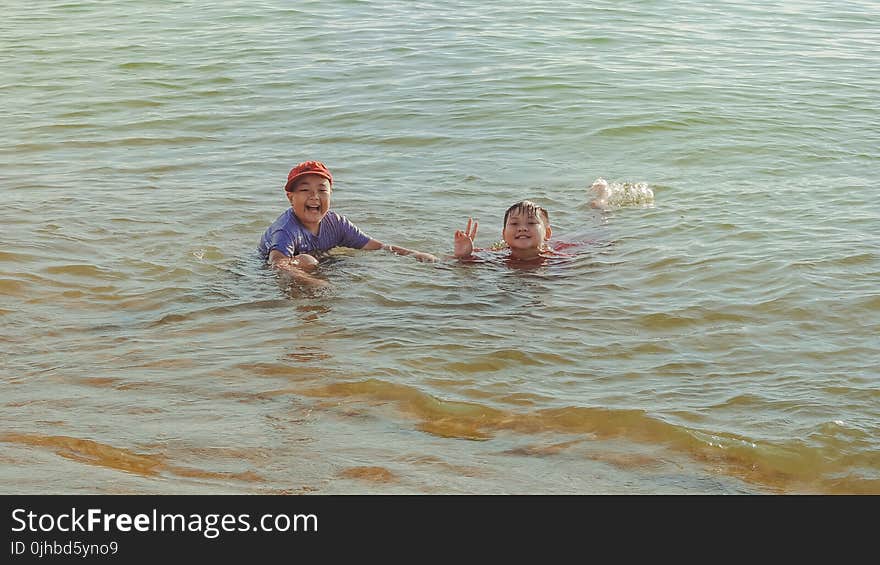 Two Boy on Brown Body of Water