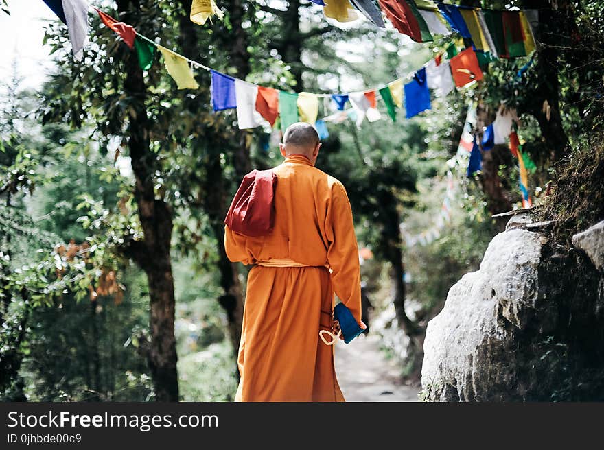 Monk Walking Near Buntings during Day