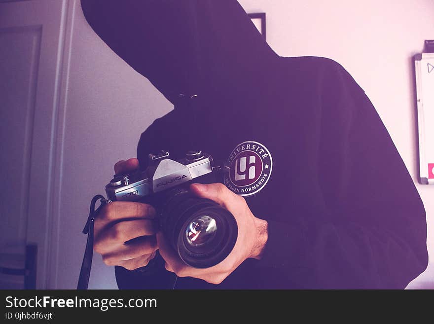 Man Holding Black and Gray Dslr Camera Inside White Wall Paint Room