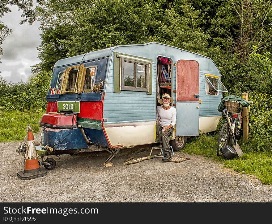 Photo Of A Man In White Long-sleeved Top on Blue And White Pop-up Camper