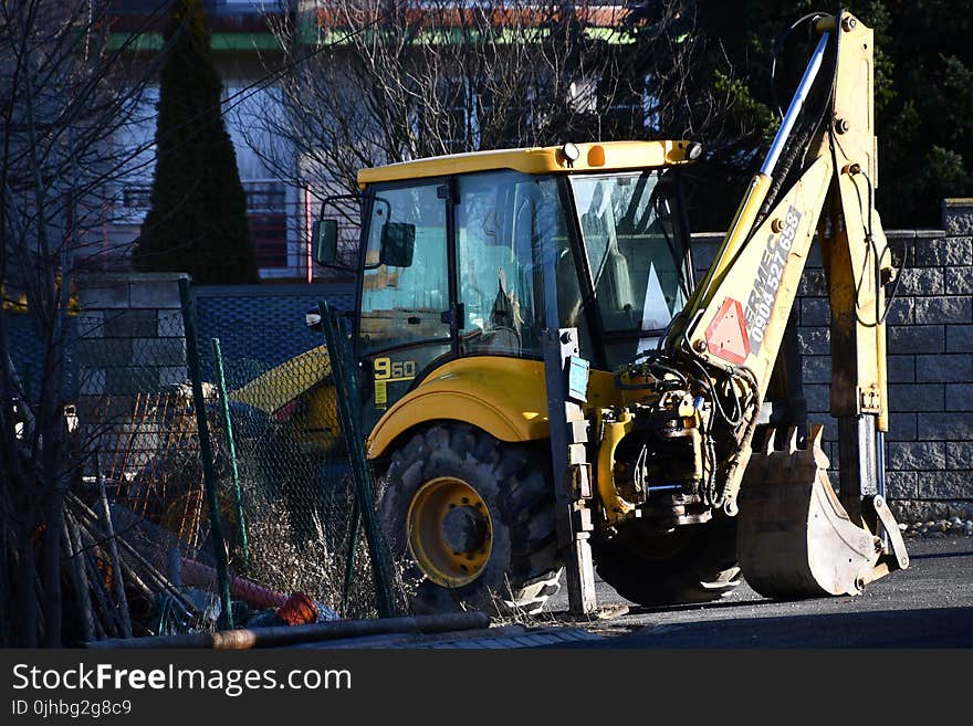 Yellow and Black Backhoe Near the Wire Fence