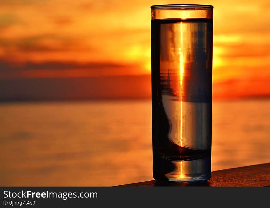 Clear Highball Glass on Brown Surface during Golden Hour