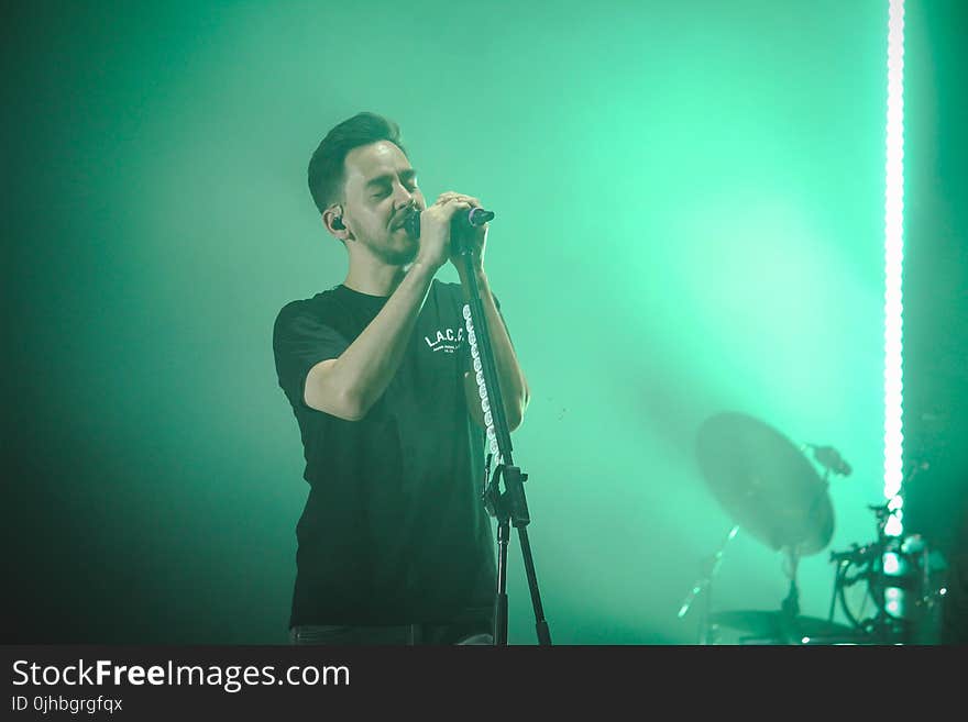 Man Wearing Black Crew-neck T-shirt Holding Microphone