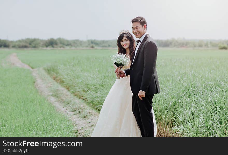 Man and Woman Wearing Wedding Dress and Suit in Between of Rice Fields