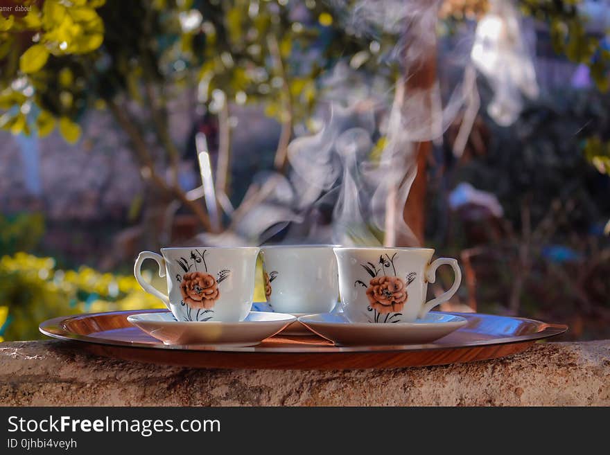 Shallow Focus Photo of Three White-brown-and-black Ceramic Floral Mugs on Saucers