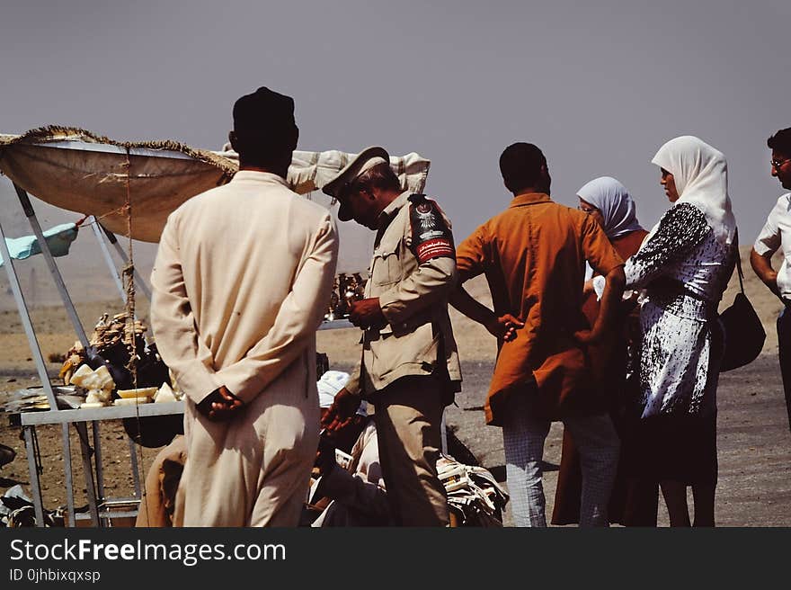 Group of People on Desert Beside Brown Tent