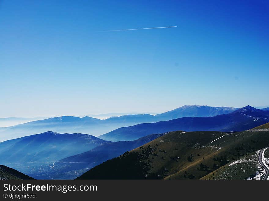 Green and Blue Fog Covered Mountains Under Blue Sky