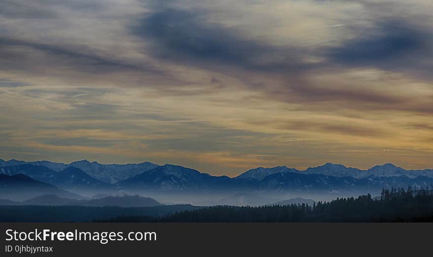 Tall Mountains Surrounded by Fogs Below the Clouds High-saturated Photography