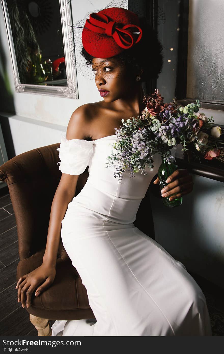 Woman Wearing White Off-shoulder Bodycon Dress Holding Flower Arrangement in Vase