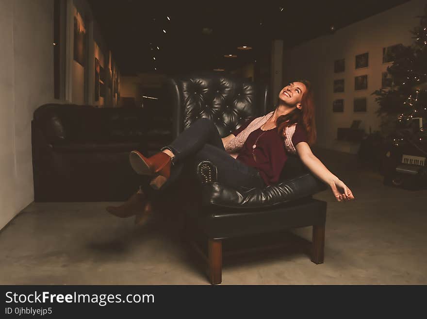 Woman in Maroon Scoop-neck Shirt Sitting on Black Leather Sofa Chair