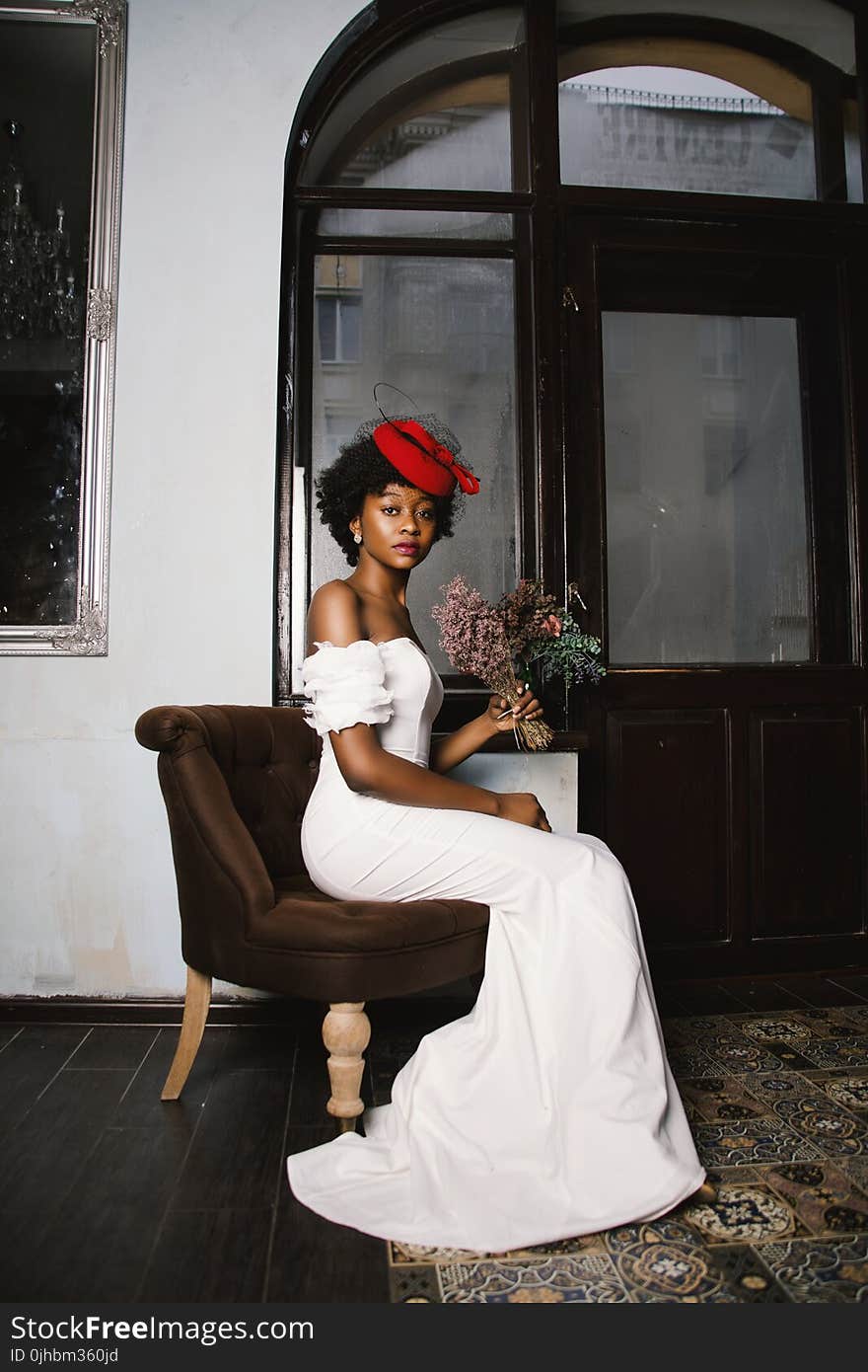 Woman in White Off-shoulder Wedding Dress Sitting in Brown Fabric Sofa Chair